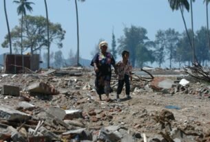 Two people walk through debris in Banda Aceh, Indonesia after a devastating tsunami.